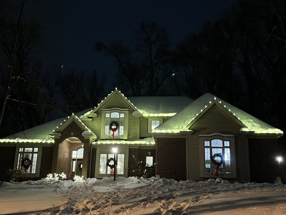 Home in the snow with lit wreaths in every window and warm white roofline lights