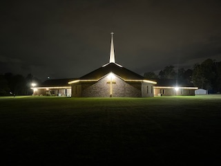 Church with warm white Christmas lights along roofline and steeple